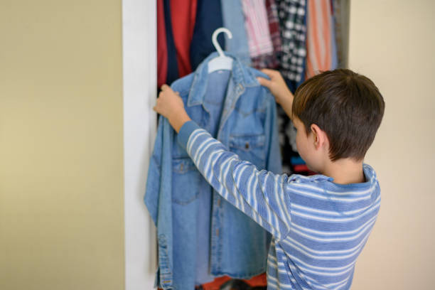 istock Boy holding a denim shirt in front of a closet 1463514031