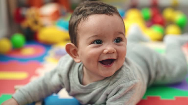 Adorable hispanic baby holding xylophone lying on floor at kindergarten