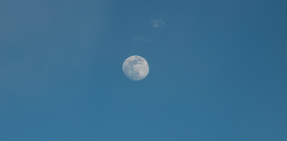 Beautiful full moon on the  blue sky in the clouds.