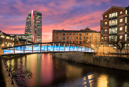 Leeds city centre at sunset. This bridge opened in February 2023 and commemorates David Oluwale, who tragically drowned in the River Aire in 1969. The image also shows Bridgewater Place, one of the city's tallest buildings.