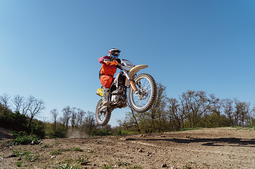 Motocross rider jumping mid air against cloudy sky.