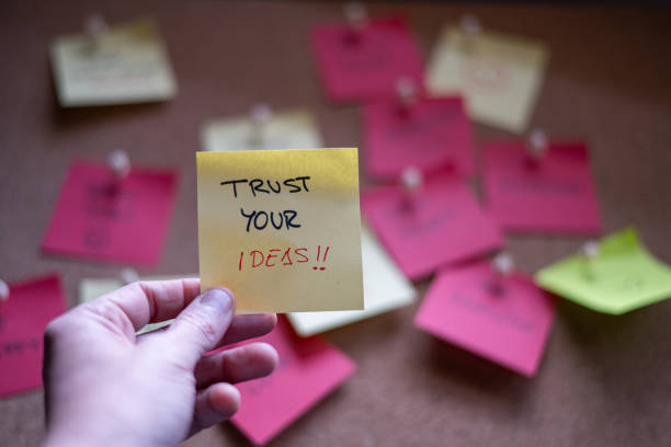 istock Hand holding handwritten paper note, TRUST YOUR IDEAS 1463536164