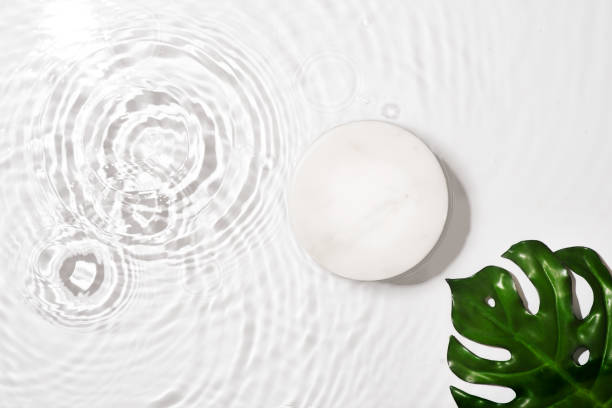 istock Transparent and clean white water background with podium and leaf, sunlight reflection 1463537182