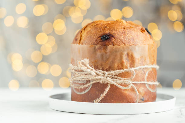 istock Traditional Italian Christmas cake Panettone on the white background. Fruit Easter cake with raisins tied with a jute thread. Festive pastry against blurred bokeh lights background 1463540275