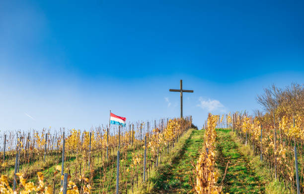 une colline avec une croix de jésus et le drapeau du luxembourg. une croix de jésus au sommet d’une colline. un paysage vallonné au luxembourg - god landscape majestic cross photos et images de collection