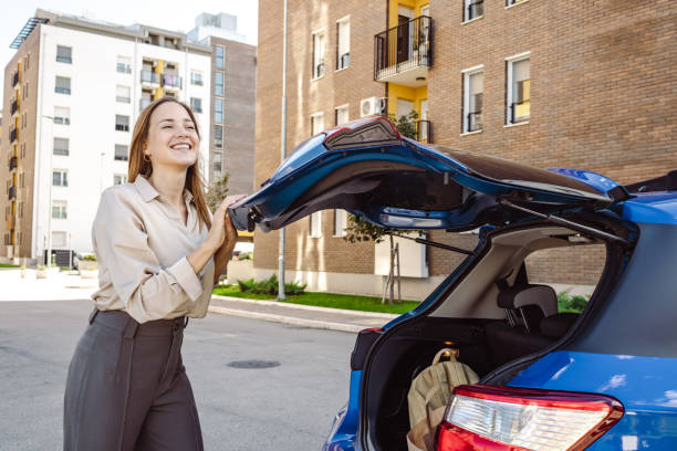 Beautiful woman closes the trunk of a car stock photo