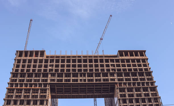 cantiere. gru edili e un edificio in costruzione su uno sfondo blu del cielo. le gru edili stanno lavorando, i muri degli edifici vengono eretti. - high rise apartments foto e immagini stock