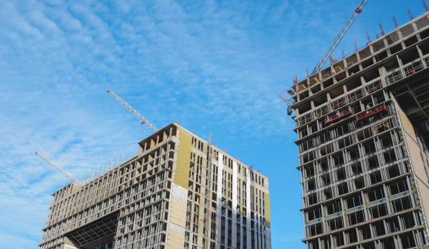 cantiere. gru edili e un edificio in costruzione su uno sfondo blu del cielo. le gru edili stanno lavorando, i muri degli edifici vengono eretti. - high rise apartments foto e immagini stock