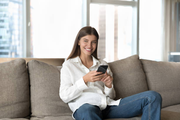 istock Happy positive young cellphone user woman sitting on home sofa 1463545887