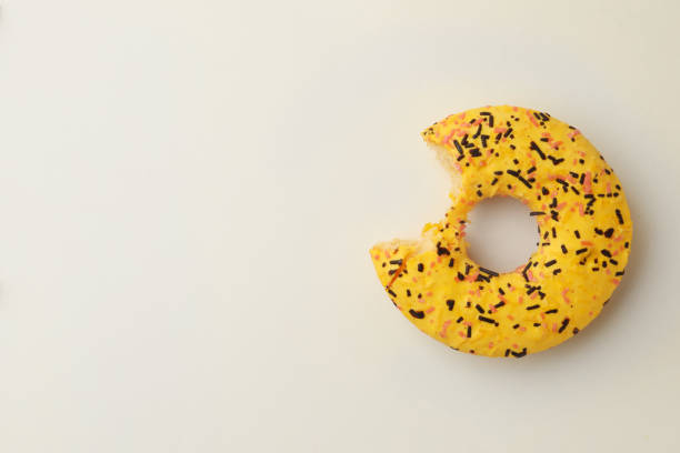 istock Delicious yellow glazed donut with bite mark on white background, top view. Space for text 1463546960