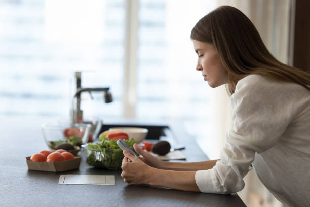 istock Serious focused chef girl using mobile phone at kitchen table 1463547002