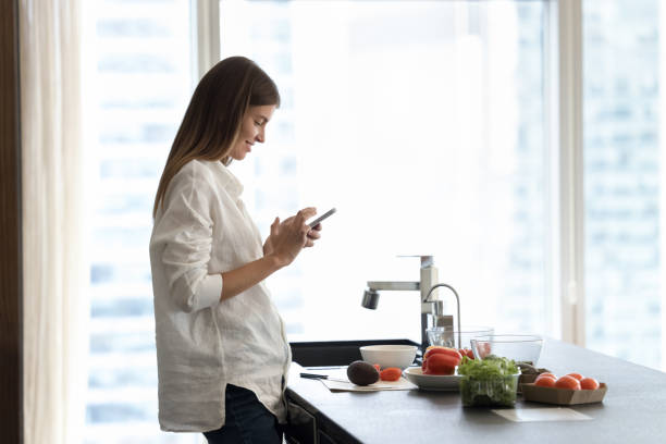 istock Happy beautiful young smartphone user girl reading recipe on internet 1463547003