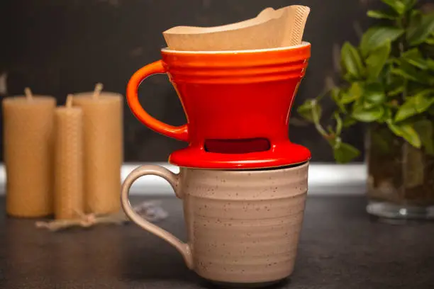 Photo of Brewing coffee in a funnel. The process of making branded coffee in a funnel on a gray wooden table. In the early morning, pour the coffee that blooms in the dropper.