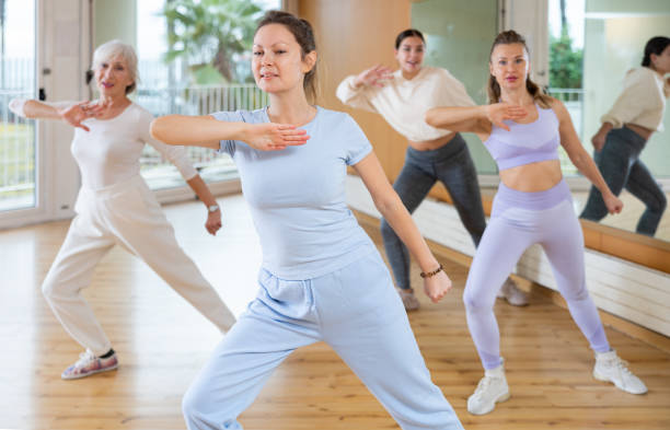 istock Cheerful energetic female dancers of different ages learning new dancing steps in modern fitness class 1463553010