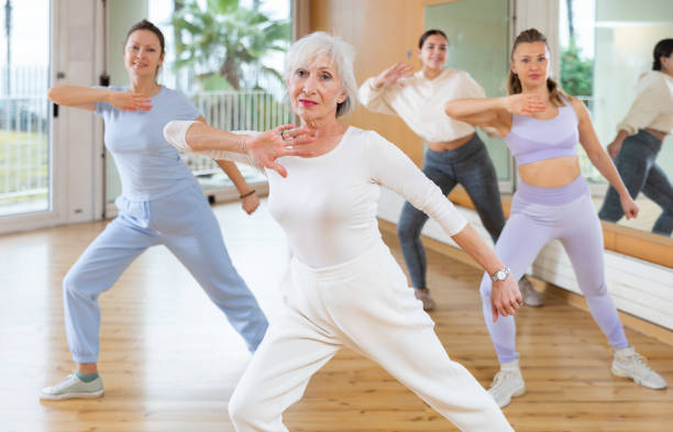 istock Active positive senior woman performing dance elements during lesson with female group in modern school for adults 1463553023