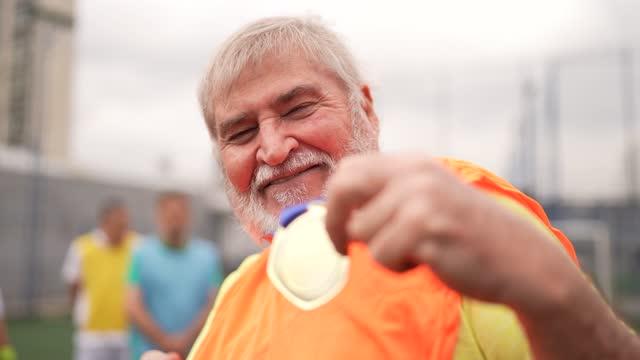 Portrait of a senior man holding the medal on the soccer field