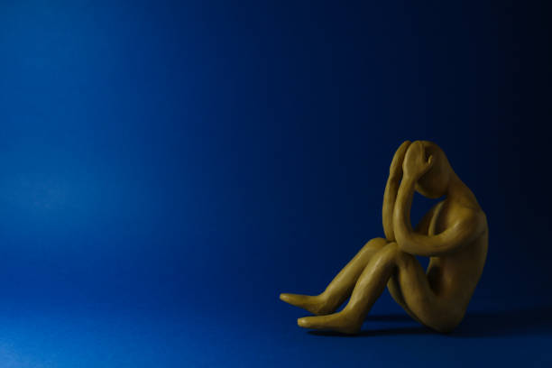 Plasticine figure of crying human on dark blue background. Space for text