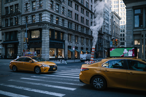 Streets of Manhattan, New York during the day. A yellow cab can be seen passing by.