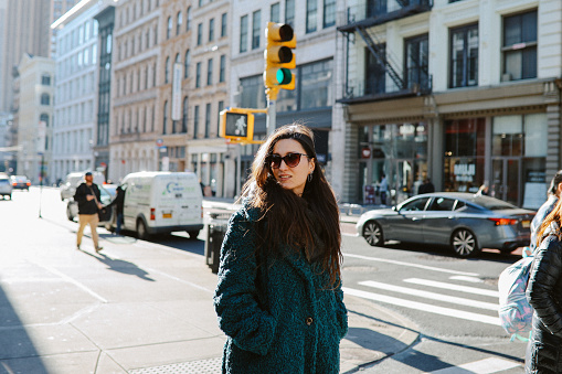 Woman in her 30s commuting through the streets of Manhattan, New York City. She is wearing a fake fur coat, on a sunny but cold winter day.