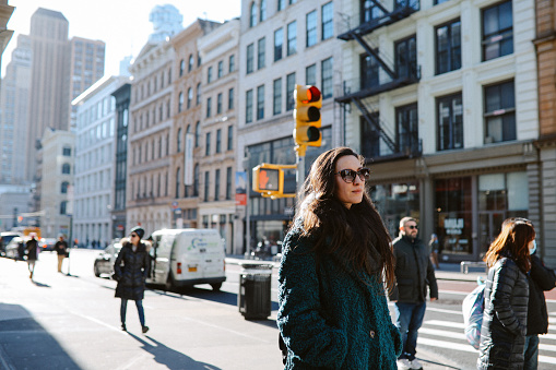 Woman in her 30s commuting through the streets of Manhattan, New York City. She is wearing a fake fur coat, on a sunny but cold winter day.