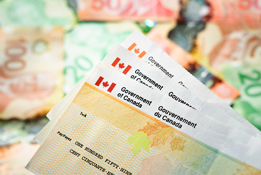 Stack of Canadian tax refund cheques with Canadian currency in the background