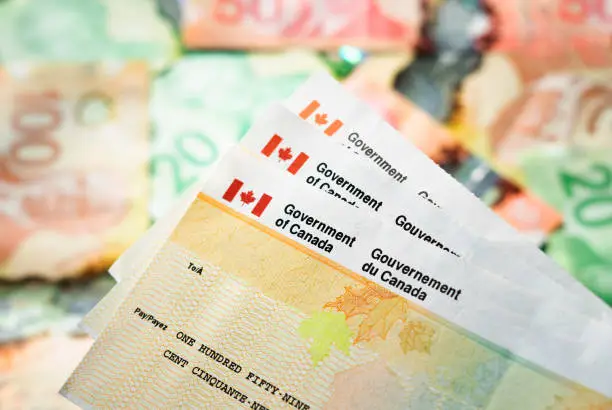 Photo of Canada Government Tax Refund Cheques with Cash in the background