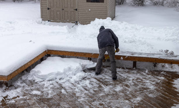Man shoveling deep snow off a wooden deck