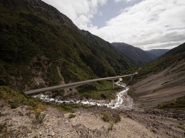 автомобили едут по бетонному мосту otira viaduct через зеленую альпийскую долину реки на перевале артурс южные альпы �новая зеландия - arthurs pass national park стоковые фото и изображения