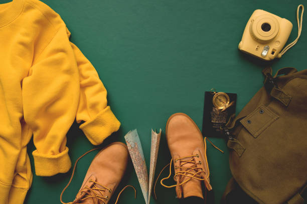 Trekking poles and hiking boots. Hiking gear without people. Ground rock and grass. Hat for protection from the sun on the backpack.
