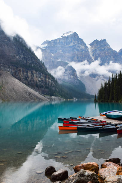 istock Colorful canoe lined up on turqoise lake surrounded by mountains 1463586448