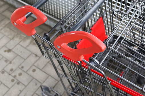 Handles of shopping trolleys in close-up in front of a supermarket