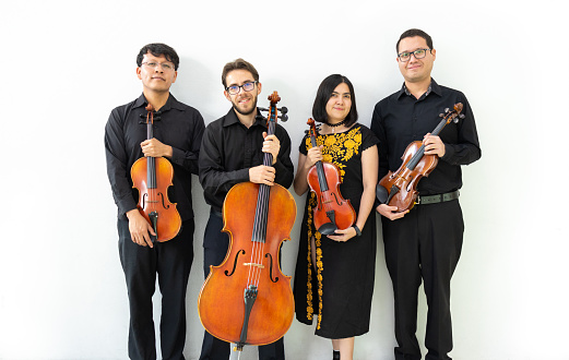 three men and a girl mixed group of musicians with wooden string instruments, standing against a white wall