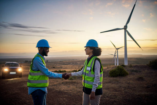 zespół inżynierów, uścisk dłoni i energia odnawialna na farmie zachodzącego słońca dla turbin wiatrowych, energii i energii elektrycznej. elektryk mężczyzna i kobieta ściskają dłonie na naturze nocne utrzymanie wiatraka umowa partnerska - alternative energy electricity wind turbine team zdjęcia i obrazy z banku zdjęć