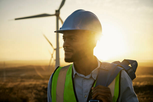 istock Renewable energy, windmill and engineer man in the countryside for industrial, development and innovation. Engineering, wind and turbine by black guy with vision for future, sustainability and power 1463615821