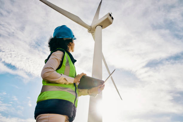 Engineer woman, wind turbine and laptop on farm for renewable energy, power and electricity. Electrician or technician in nature for windmill, eco and green environment inspection and maintenance stock photo