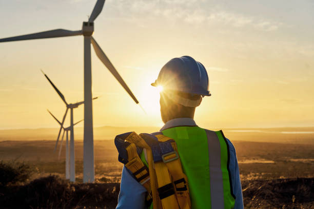 Engineer, renewable energy and windmill rear view of man at a field for industrial, development and innovation. Engineering, wind and turbine by guy with vision for future, sustainability and power Engineer, renewable energy and windmill rear view of man at a fied for industrial, development and innovation. Engineering, wind and turbine by guy with vision for future, sustainability and power windmill sunset stock pictures, royalty-free photos & images