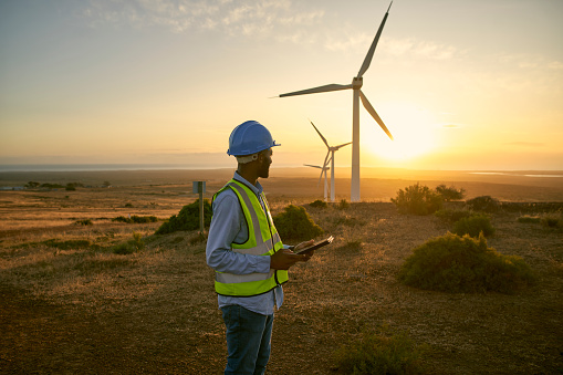 Wind turbine, field and engineering man with renewable energy for countryside, sustainability and farming technology. Clean energy, sustainable and electricity windmill of person on tablet in sunset
