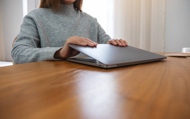 istock Closeup image of a woman closing or opening a laptop computer on table after finished using it 1463622254