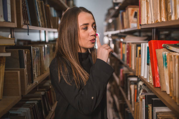 istock While standing between the bookshelves, the lovely librarian signals for silence 1463628596
