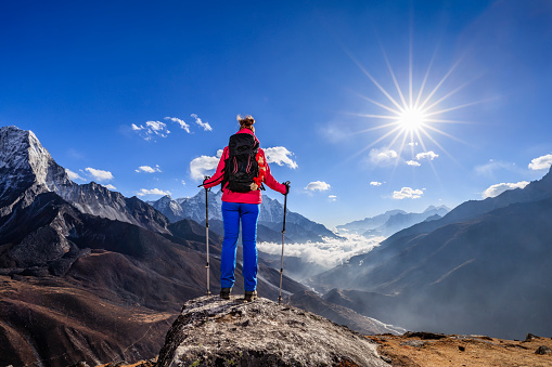 Young woman, wearing red jacket, is standing on the top of a mountain and watching sunset over Himalayas .Mount Everest National Park. This is the highest national park in the world, with the entire park located above 3,000 m ( 9,700 ft). This park includes three peaks higher than 8,000 m, including Mt Everest. Therefore, most of the park area is very rugged and steep, with its terrain cut by deep rivers and glaciers. Unlike other parks in the plain areas, this park can be divided into four climate zones because of the rising altitude.