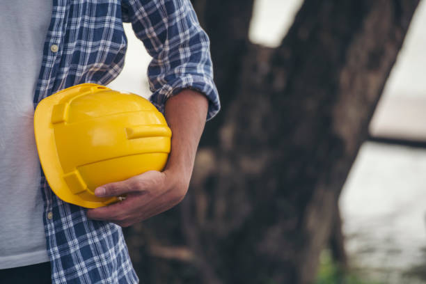 istock Engineer man hands holding hardhat white work helmet hard hat for Civil Construction Engineering. Construction engineer man in safety suit hold white work helmet hard hat on hands at Construction Site 1463629697