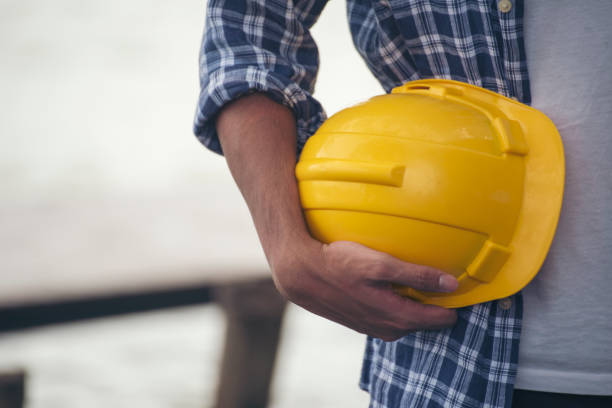 Engineer man hands holding hardhat white work helmet hard hat for Civil Construction Engineering. Construction engineer man in safety suit hold white work helmet hard hat on hands at Construction Site