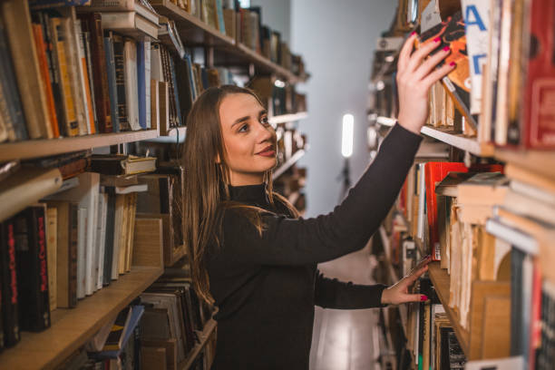 istock Gorgeous librarian takes a book from the shelf in the library 1463634123