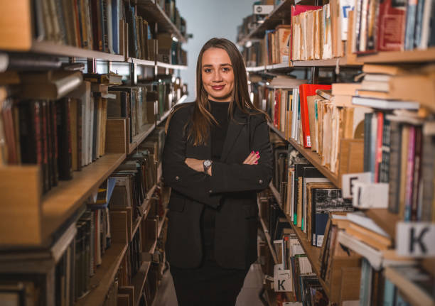 istock Portrait of a librarian standing with folded arms between bookshelves in a library 1463634372