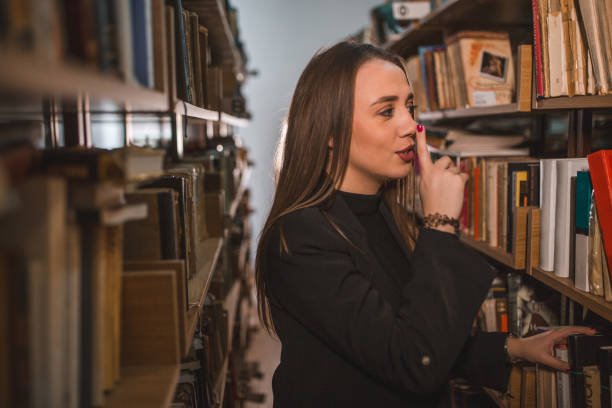 istock While standing between the bookshelves, the beautiful librarian signals for silence 1463635609