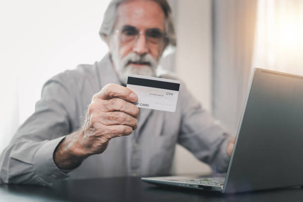 istock Senior elderly grey haired moustache bearded man using credit bank card and laptop transferring money purchases online shopping. People lifestyle concept. 1463636992