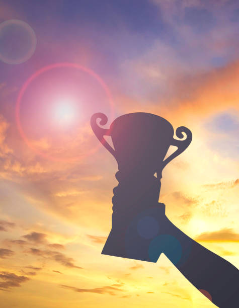 istock silhouette hand hold trophy and sunset background 1463639802