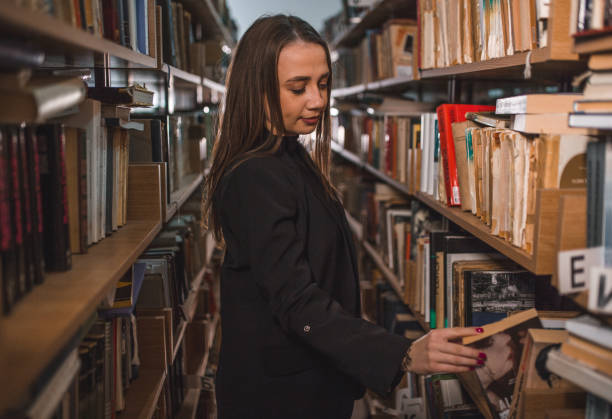 istock Lovely librarian takes a book from the shelf in the library 1463640296