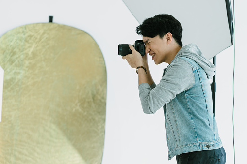 Asian Photographer shooting in Studio with studio strobe in background