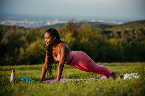 Shot of a young athletic black woman doing a plank exercise outdoors.